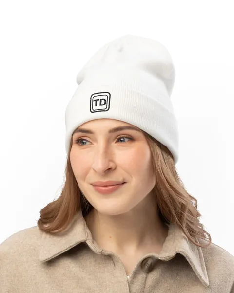 Frau mit weißer, bestickter TINNKEO-Beanie