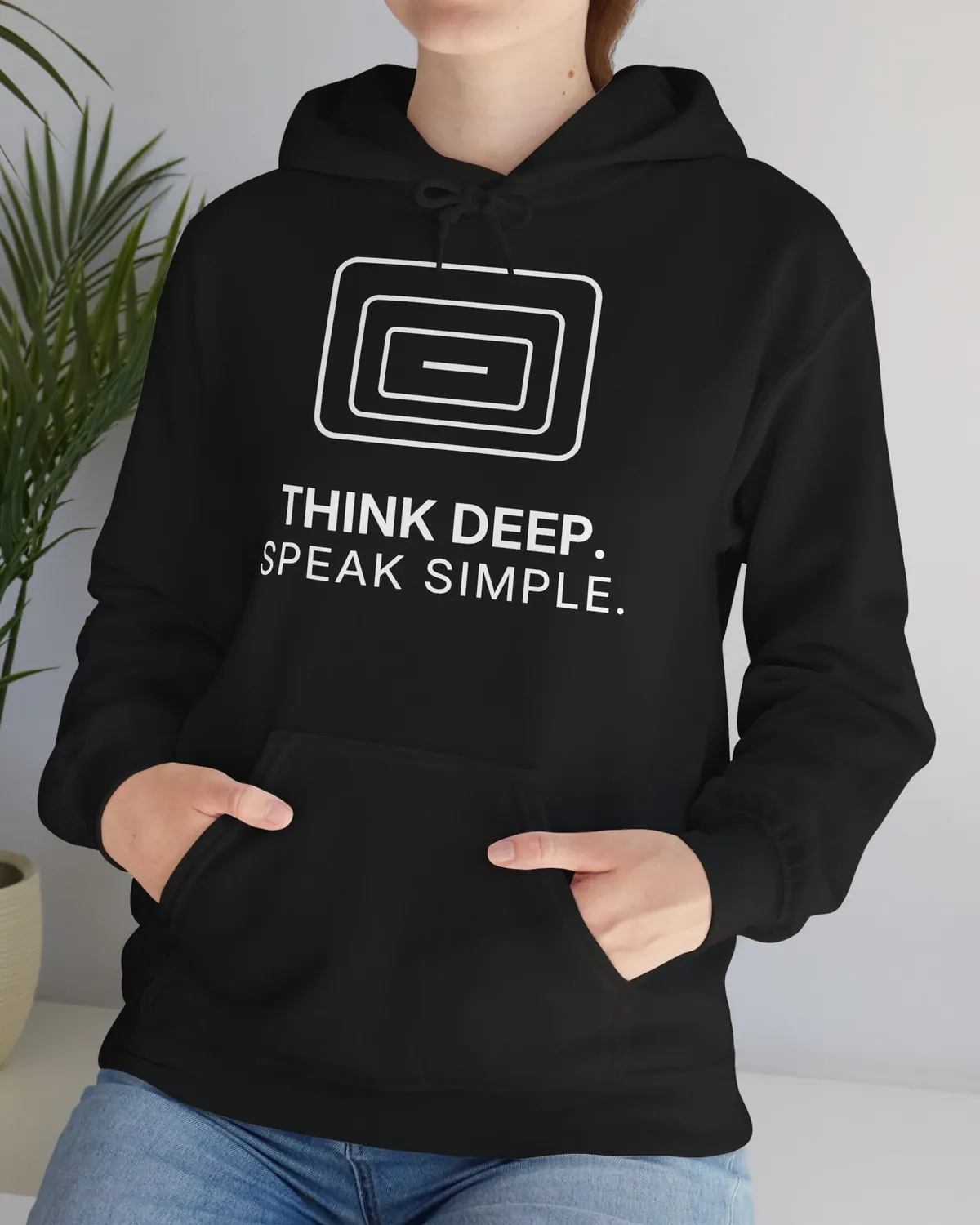 Person im schwarzen TINNKEO-Hoodie mit dem Aufdruck „Think deep. Speak simple.“, Hände in der Bauchtasche