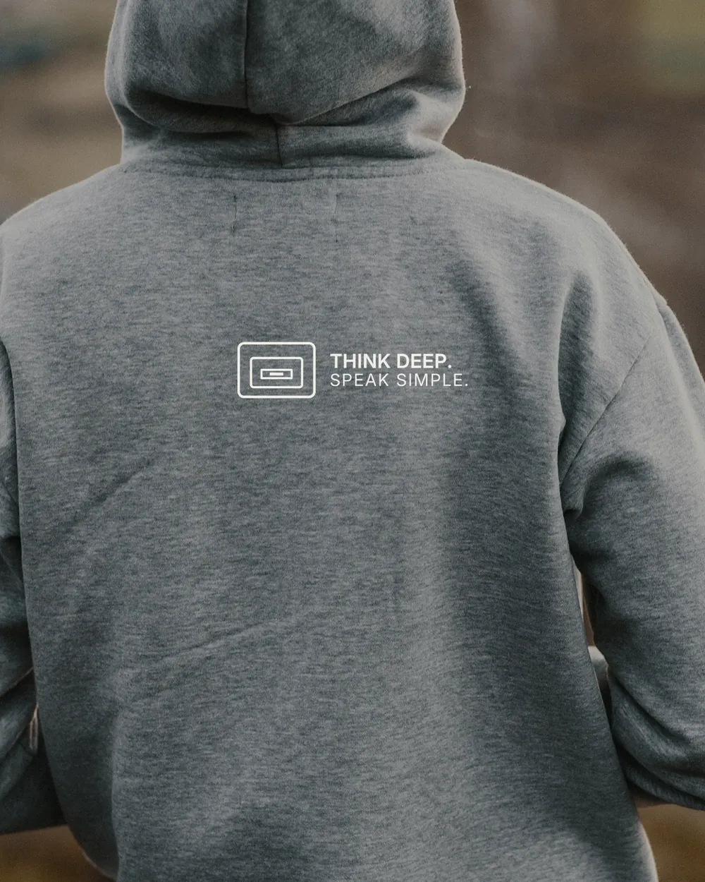 Rückenansicht einer Person im grauen Hoodie mit kleinem TINNKEO-Aufdruck